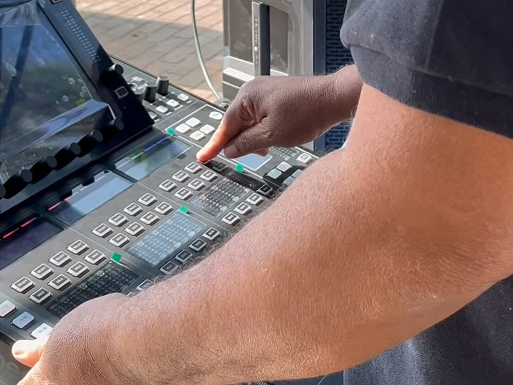 Técnico de som da IS operando uma mesa digital num evento ao ar livre