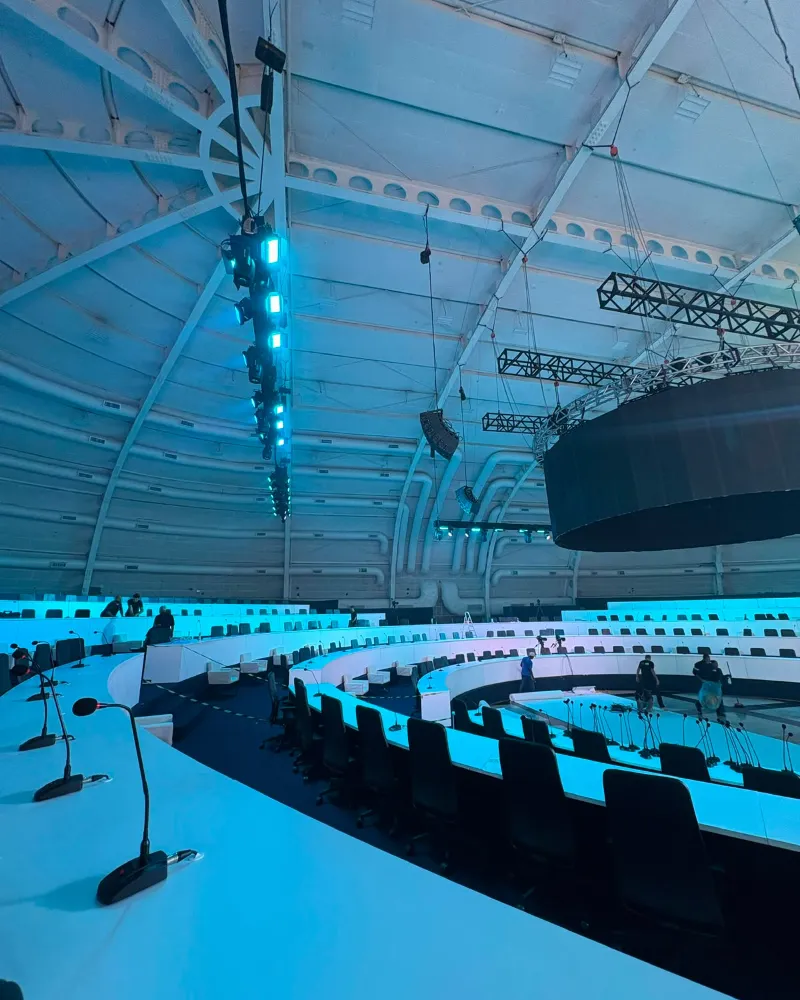 Plenário em semicírculo no WTC São Paulo, com microfones de mesa, line array e luz suspensos no teto
